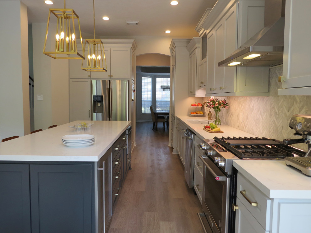 Mid-sized transitional l-shaped eat-in kitchen in Houston with shaker cabinets, grey cabinets, quartz benchtops, white splashback, marble splashback, stainless steel appliances, vinyl floors, with island, beige floor, white benchtop and an undermount sink.