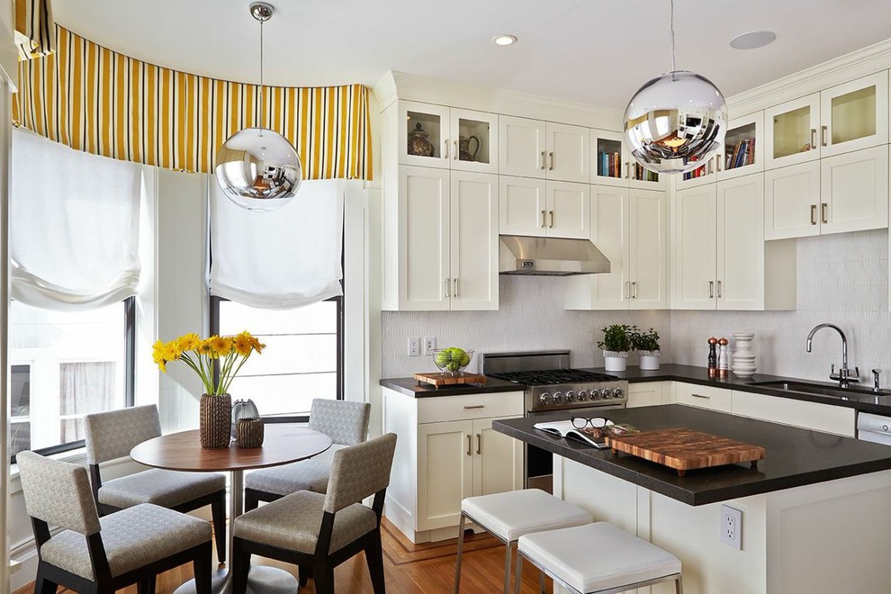 This is an example of a mid-sized transitional l-shaped eat-in kitchen in San Francisco with a drop-in sink, shaker cabinets, white cabinets, quartz benchtops, white splashback, ceramic splashback, stainless steel appliances, medium hardwood floors and with island.