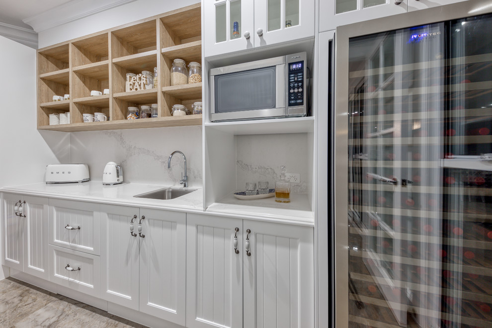 Inspiration for a mid-sized country galley kitchen pantry in Sunshine Coast with an undermount sink, shaker cabinets, white cabinets, quartz benchtops, white splashback, stone slab splashback, white appliances, marble floors, with island, grey floor and white benchtop.