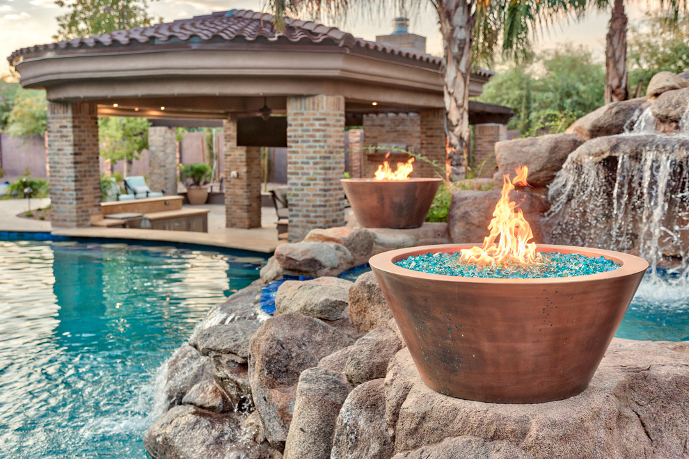 This is an example of a large mediterranean backyard natural pool in Phoenix with natural stone pavers.