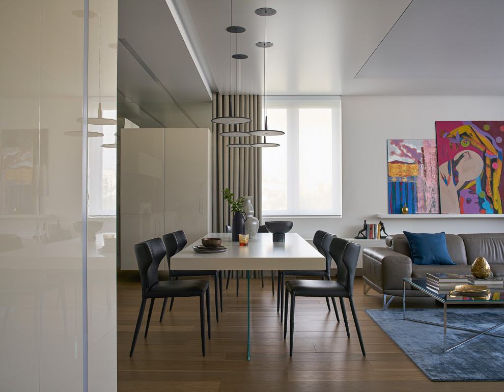 Идея дизайна: гостиная-столовая среднего размера в современном стиле с серыми стенами, паркетным полом среднего тона, коричневым полом, многоуровневым потолком и панелями на части стены без камина
