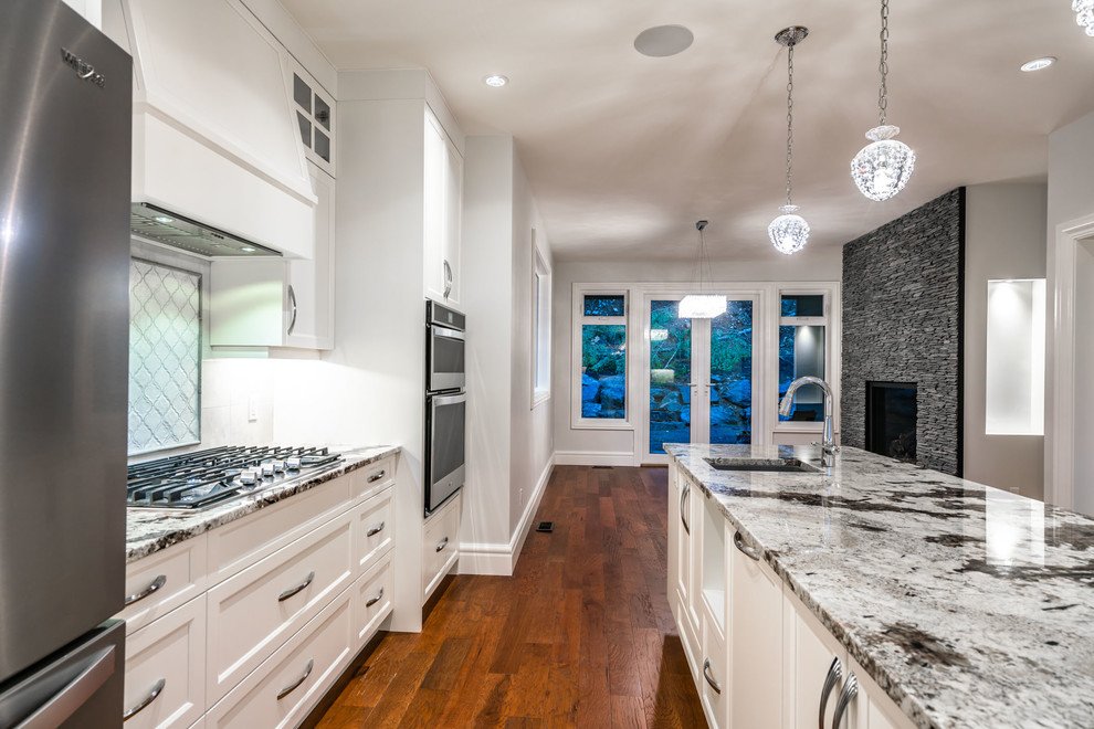 Eat-in kitchen - large transitional u-shaped dark wood floor and brown floor eat-in kitchen idea with an undermount sink, recessed-panel cabinets, white cabinets, granite countertops, white backsplash, ceramic backsplash, stainless steel appliances, an island and multicolored countertops