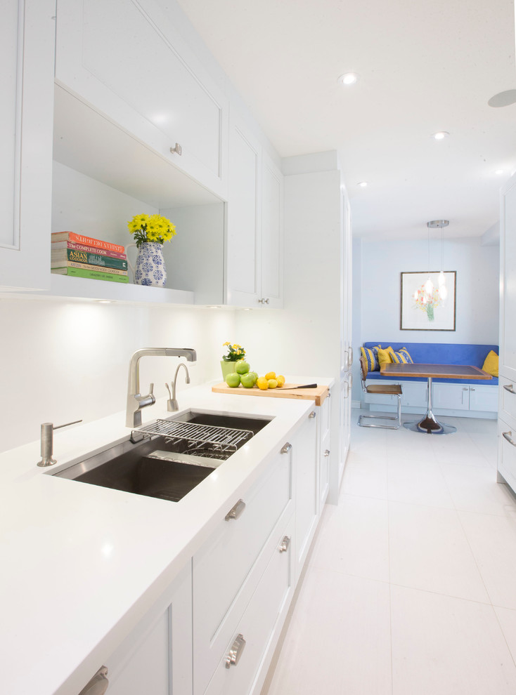 Large contemporary galley kitchen in Toronto with a double-bowl sink, shaker cabinets, white cabinets, quartz benchtops, white splashback and porcelain floors.