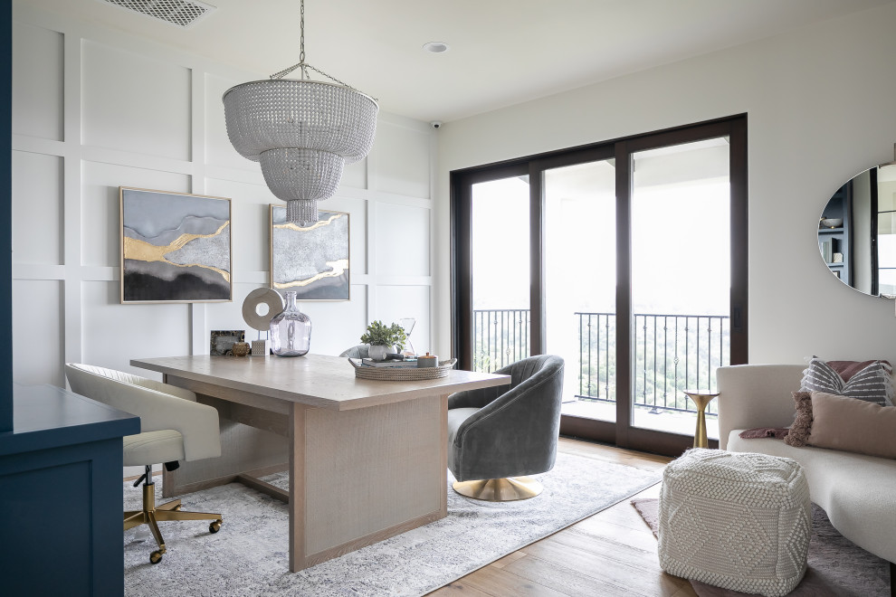 Photo of a transitional home office in Los Angeles with white walls, light hardwood floors, a freestanding desk, beige floor and panelled walls.