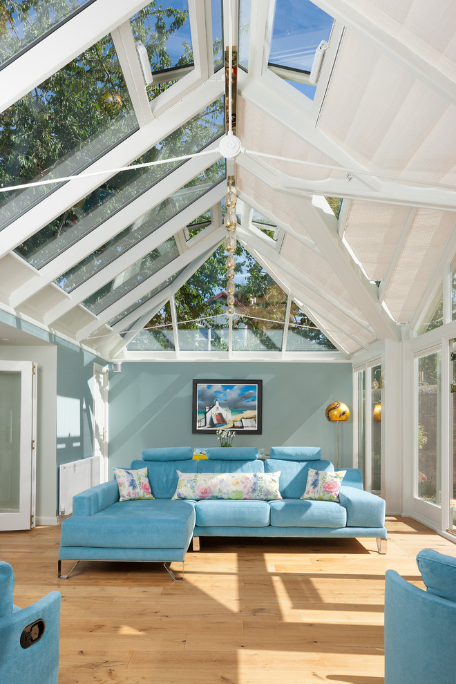 This is an example of a transitional sunroom in Edinburgh with light hardwood floors and a glass ceiling.