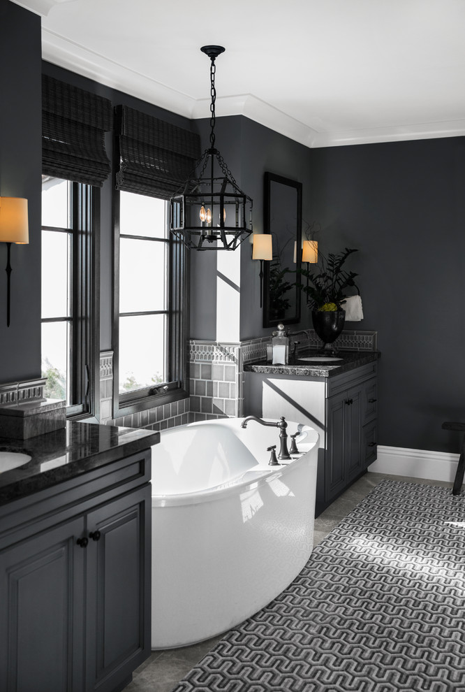 Inspiration for a transitional 3/4 bathroom in San Diego with raised-panel cabinets, black cabinets, a freestanding tub, gray tile, black walls, an undermount sink, grey floor and black benchtops.