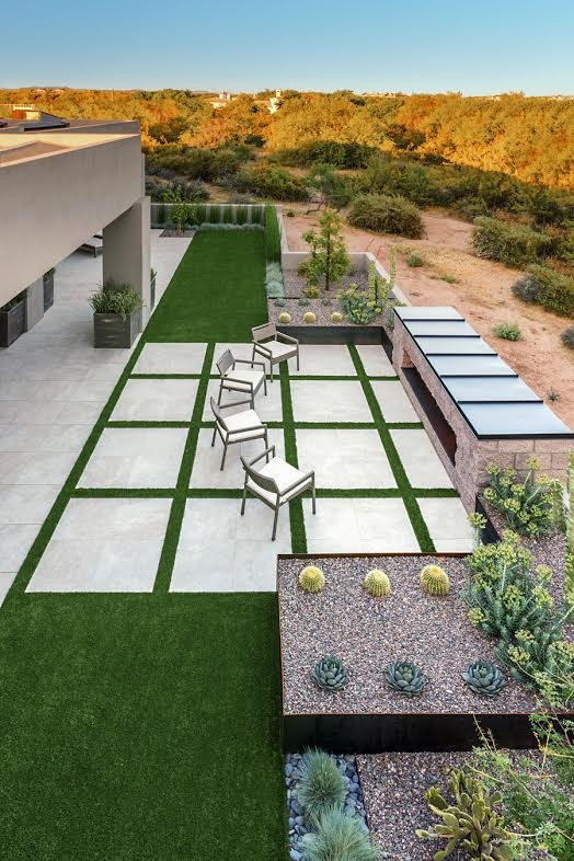 This is an example of a large modern backyard patio in Phoenix with a fire feature, concrete slab and a roof extension.