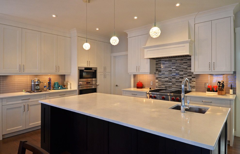 Example of a mid-sized transitional u-shaped dark wood floor eat-in kitchen design in Calgary with an undermount sink, recessed-panel cabinets, white cabinets, brown backsplash, glass tile backsplash, stainless steel appliances and an island
