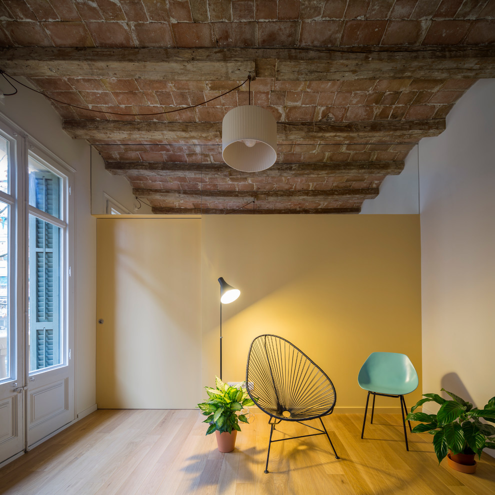 Imagen de sala de estar urbana pequeña sin chimenea y televisor con paredes amarillas y suelo de madera en tonos medios