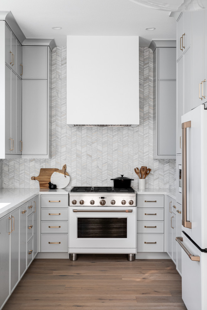 Idéer för avskilda, små funkis vitt u-kök, med en undermonterad diskho, skåp i shakerstil, grå skåp, bänkskiva i kvarts, vitt stänkskydd, stänkskydd i marmor, vita vitvaror, mellanmörkt trägolv och brunt golv
