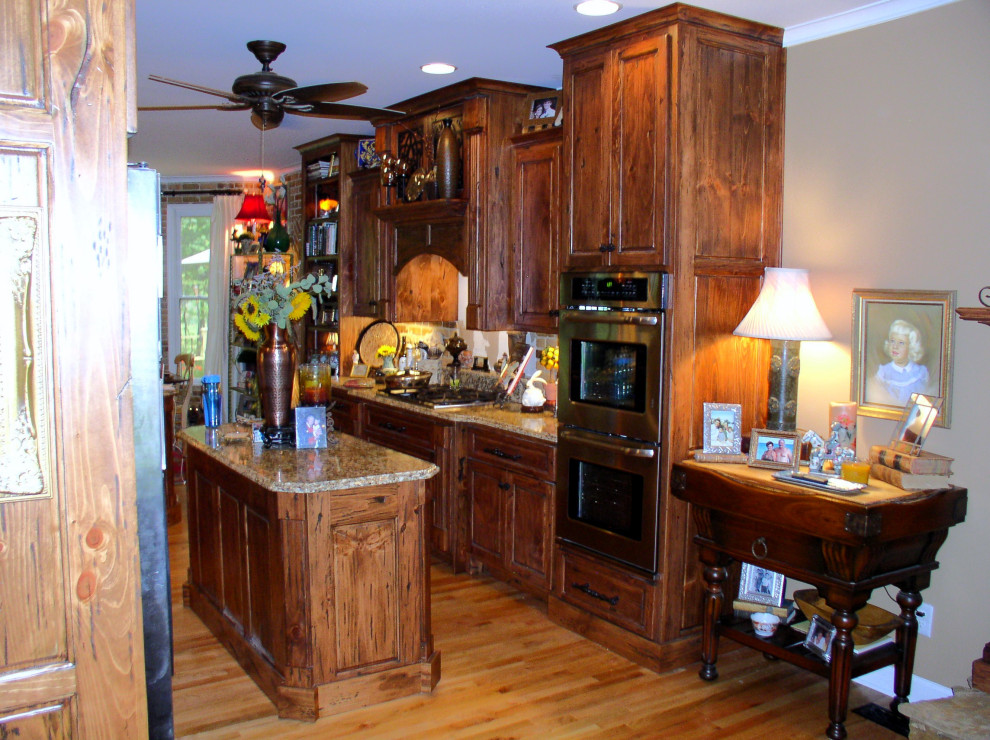 Kitchen - mid-sized galley medium tone wood floor and brown floor kitchen idea in Atlanta with an undermount sink, raised-panel cabinets, medium tone wood cabinets, granite countertops, stainless steel appliances, an island and multicolored countertops