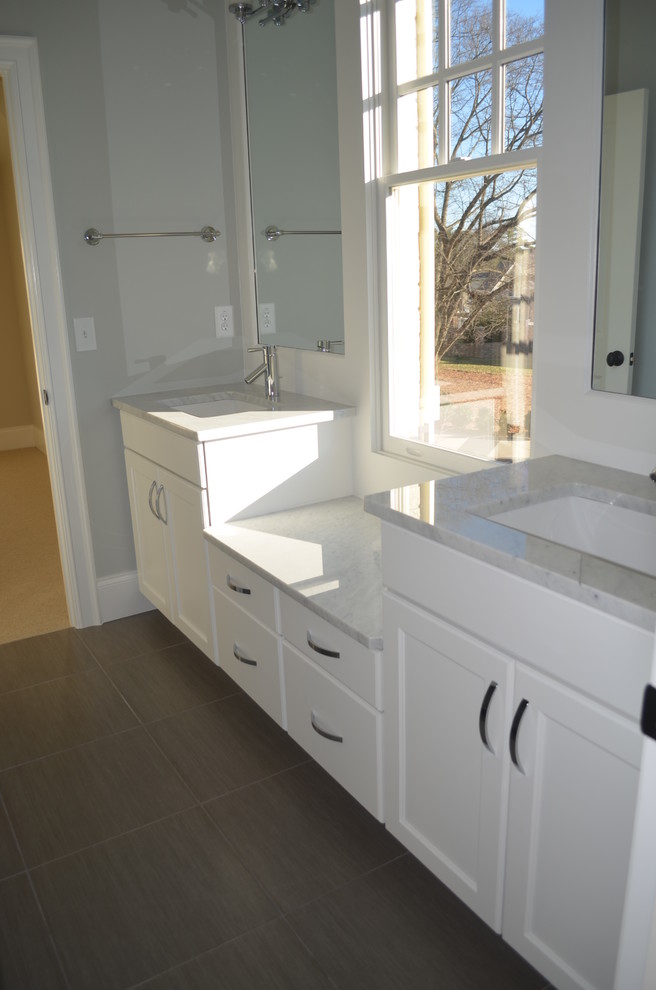 Design ideas for a large contemporary master bathroom in Raleigh with recessed-panel cabinets, white cabinets, grey walls, porcelain floors, an undermount sink, granite benchtops and brown floor.