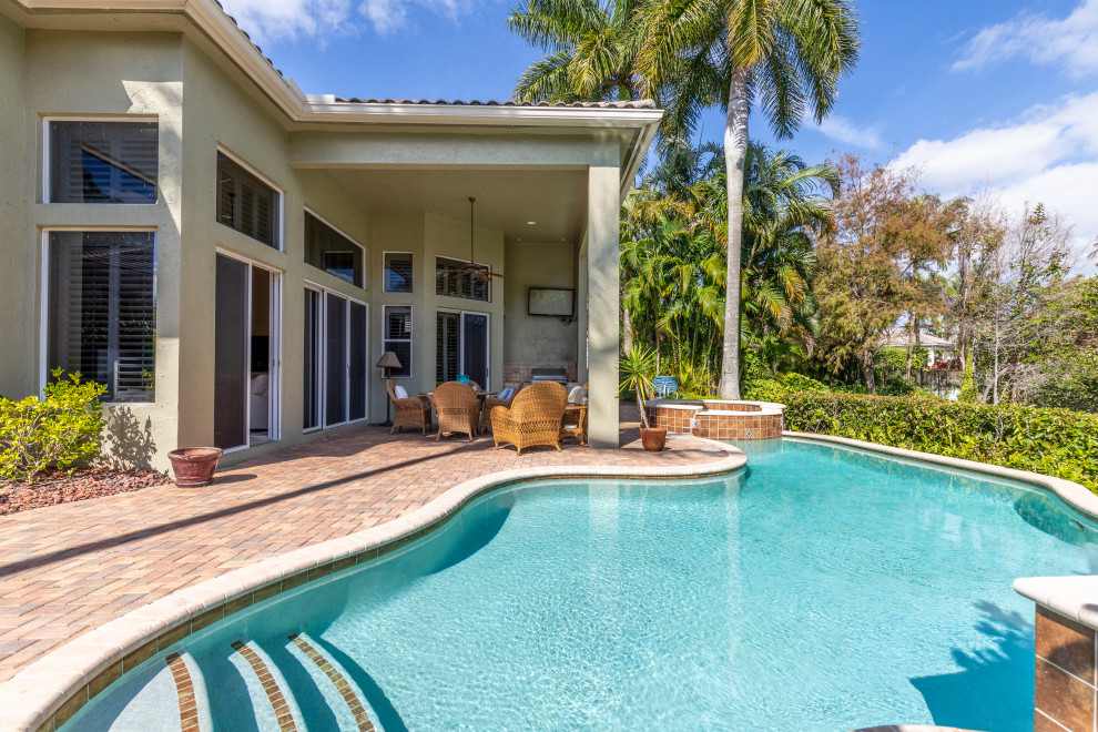 Esempio di una grande piscina naturale tropicale personalizzata dietro casa con paesaggistica bordo piscina e pavimentazioni in mattoni