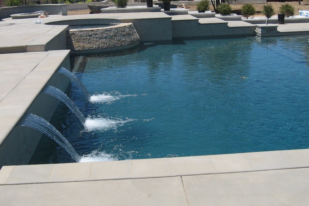 This is an example of a mid-sized modern backyard custom-shaped natural pool in San Diego with a hot tub and concrete slab.