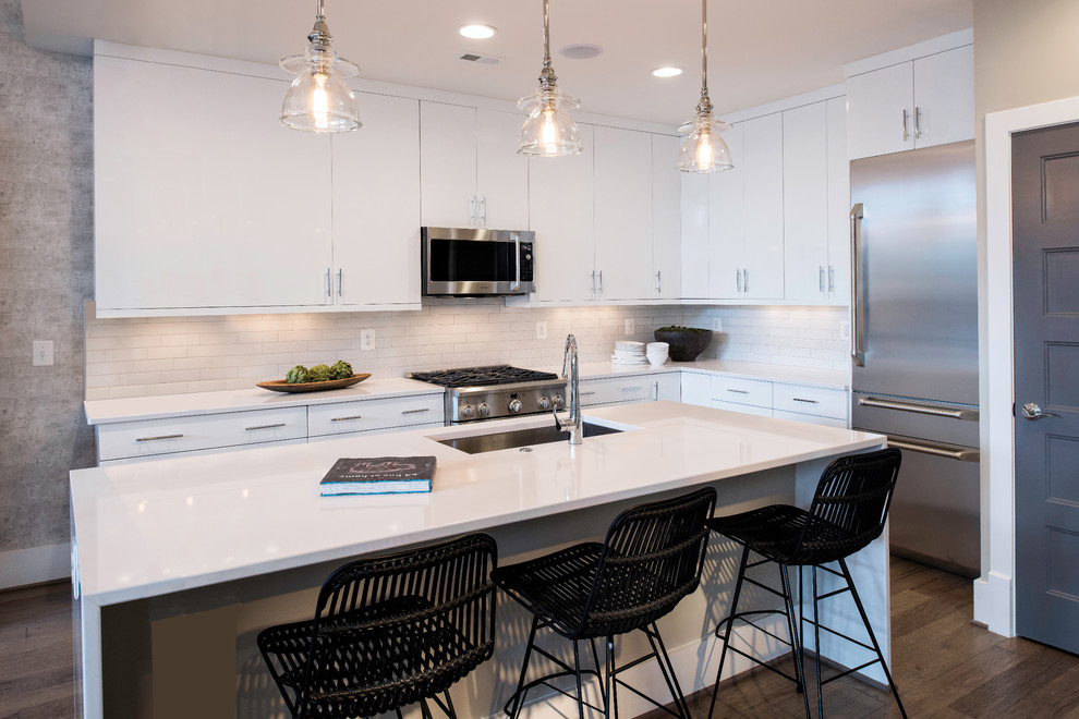 Design ideas for a contemporary l-shaped kitchen in DC Metro with an undermount sink, flat-panel cabinets, white cabinets, white splashback, subway tile splashback, stainless steel appliances, dark hardwood floors, with island and brown floor.