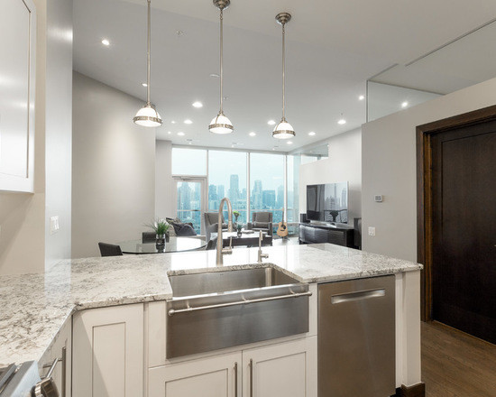 Photo of a mid-sized contemporary u-shaped eat-in kitchen in Chicago with a farmhouse sink, shaker cabinets, white cabinets, marble benchtops, beige splashback, subway tile splashback, stainless steel appliances, medium hardwood floors and no island.