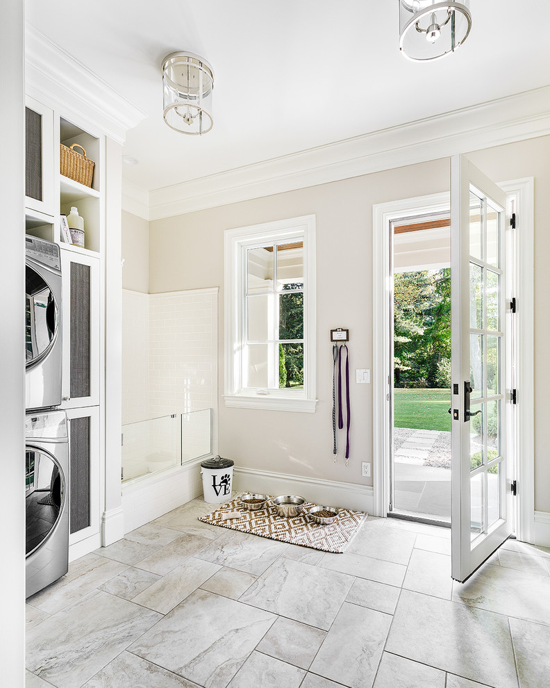 Design ideas for a large transitional utility room in Chicago with white cabinets, beige walls, ceramic floors, a stacked washer and dryer and grey floor.