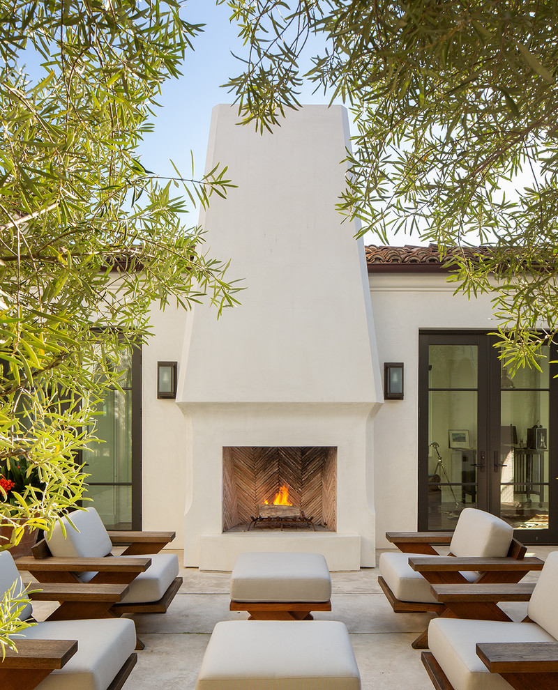 Photo of a mediterranean backyard patio in San Diego with with fireplace, concrete slab and no cover.