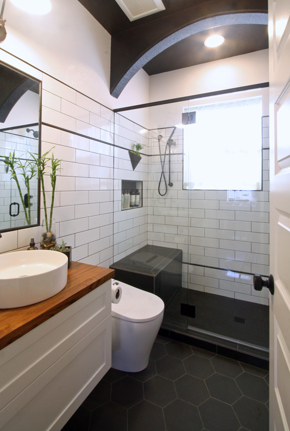 Inspiration for a small industrial bathroom in Portland with shaker cabinets, white cabinets, an alcove shower, a one-piece toilet, white tiles, metro tiles, white walls, porcelain flooring, a vessel sink, wooden worktops, black floors, a hinged door, brown worktops, a shower bench, a single sink, a floating vanity unit and wainscoting.