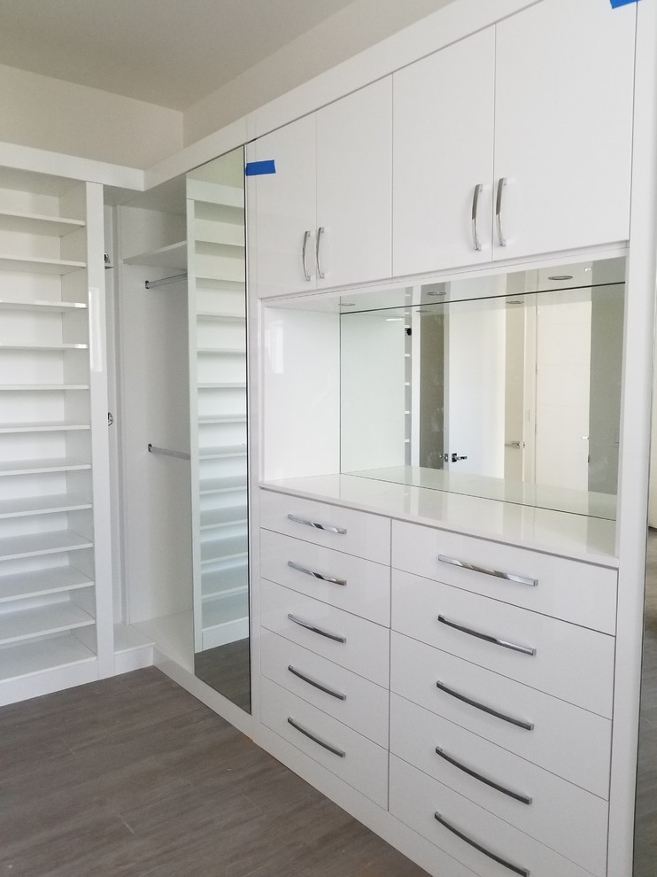 Inspiration for a large contemporary women's walk-in wardrobe in Miami with flat-panel cabinets and white cabinets.