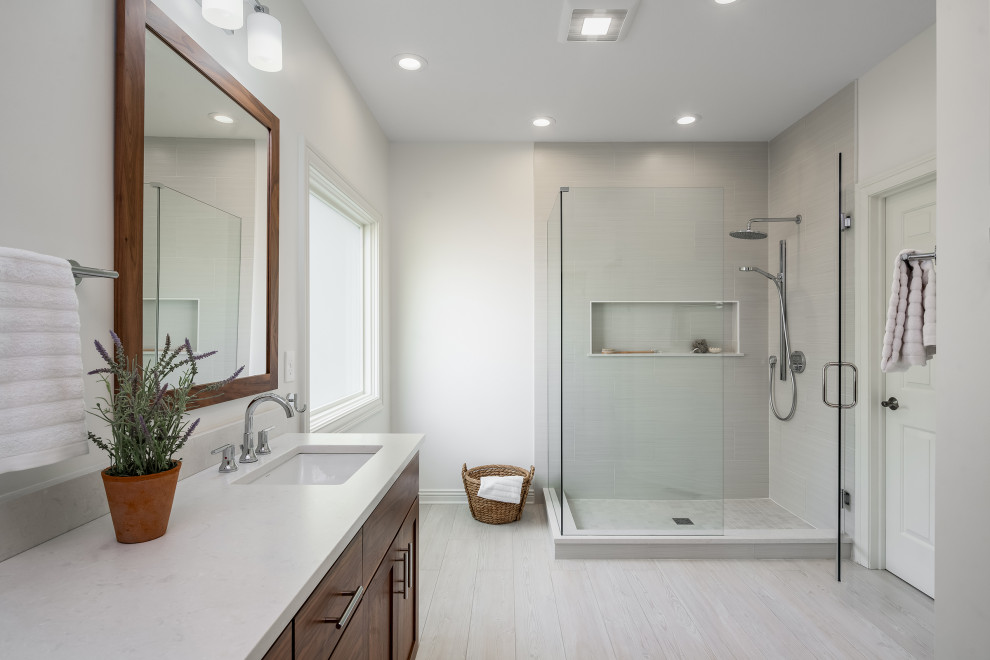 This is an example of a large modern master bathroom in Columbus with shaker cabinets, medium wood cabinets, a corner shower, white walls, ceramic floors, an undermount sink, engineered quartz benchtops, a hinged shower door, white benchtops, a niche, a double vanity and a freestanding vanity.