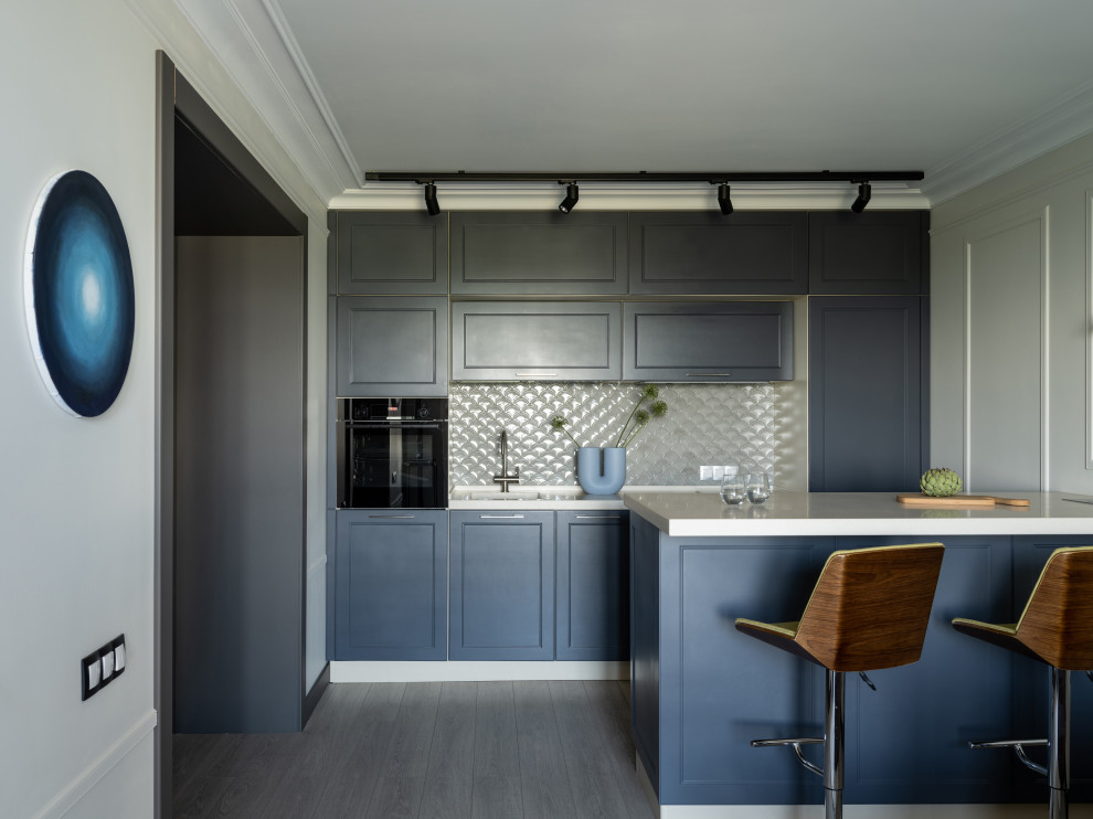This is an example of a transitional single-wall open plan kitchen in Moscow with blue cabinets, white splashback, black appliances, with island, grey floor and white benchtop.