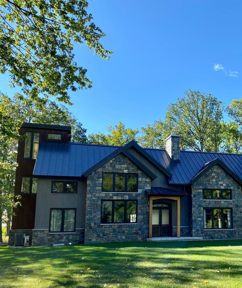 Inspiration for a large rustic gray three-story stone gable roof remodel with a metal roof and a brown roof