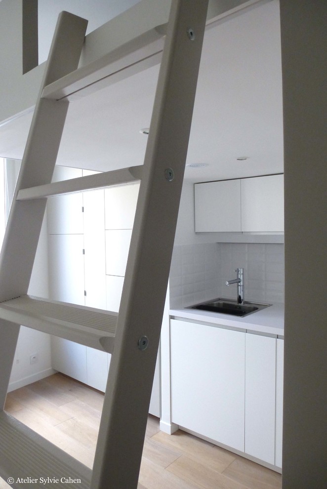 Aménagement d'une petite cuisine contemporaine avec des portes de placard blanches.