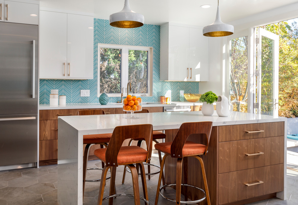 Photo of a large midcentury u-shaped kitchen in Los Angeles with an undermount sink, flat-panel cabinets, blue splashback, stainless steel appliances, with island, grey floor, medium wood cabinets, quartzite benchtops, glass tile splashback and cement tiles.