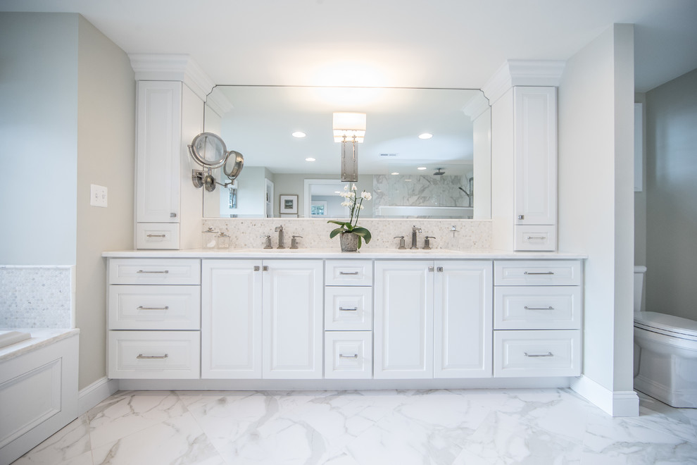 Design ideas for a large country master bathroom in DC Metro with raised-panel cabinets, white cabinets, a drop-in tub, white tile, stone tile, grey walls, marble floors, an undermount sink, marble benchtops, a two-piece toilet, multi-coloured floor and white benchtops.