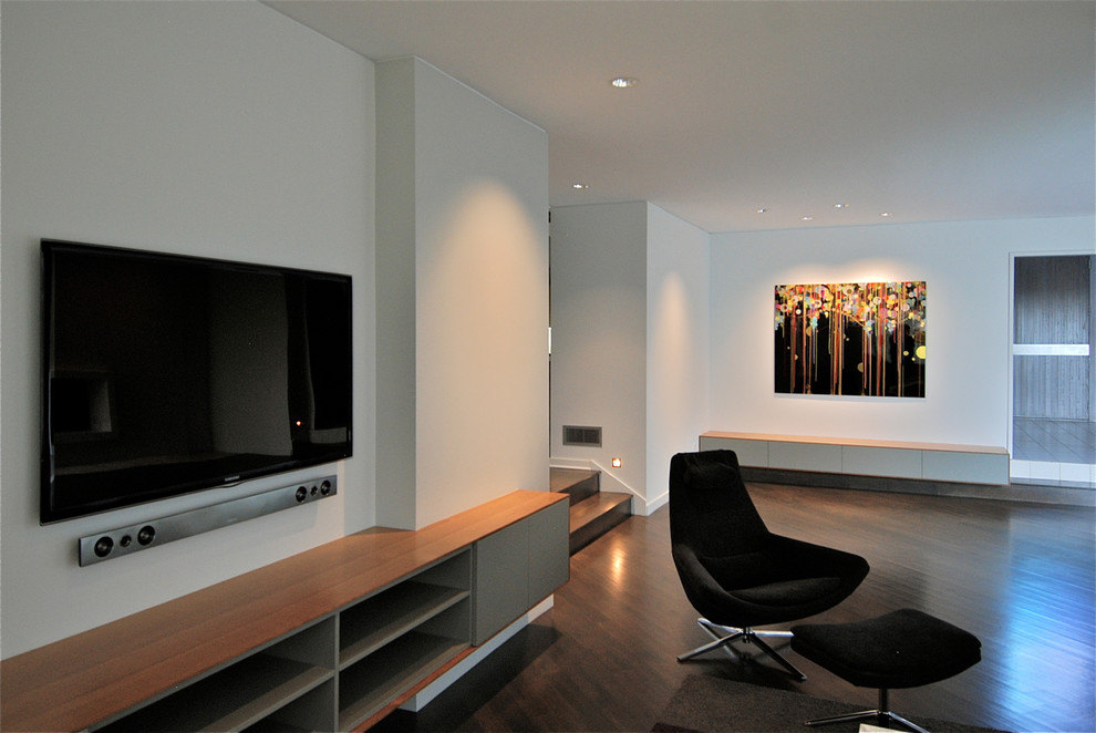 Photo of a modern open concept living room in Kansas City with grey walls, dark hardwood floors and a wall-mounted tv.