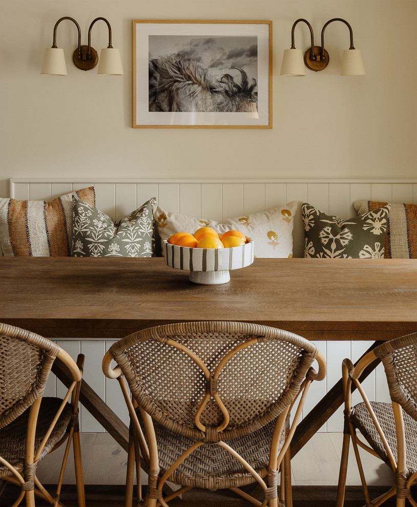 Aménagement d'une petite salle à manger éclectique avec une banquette d'angle, un mur beige, un sol en bois brun, un poêle à bois, un manteau de cheminée en brique, un sol marron et poutres apparentes.