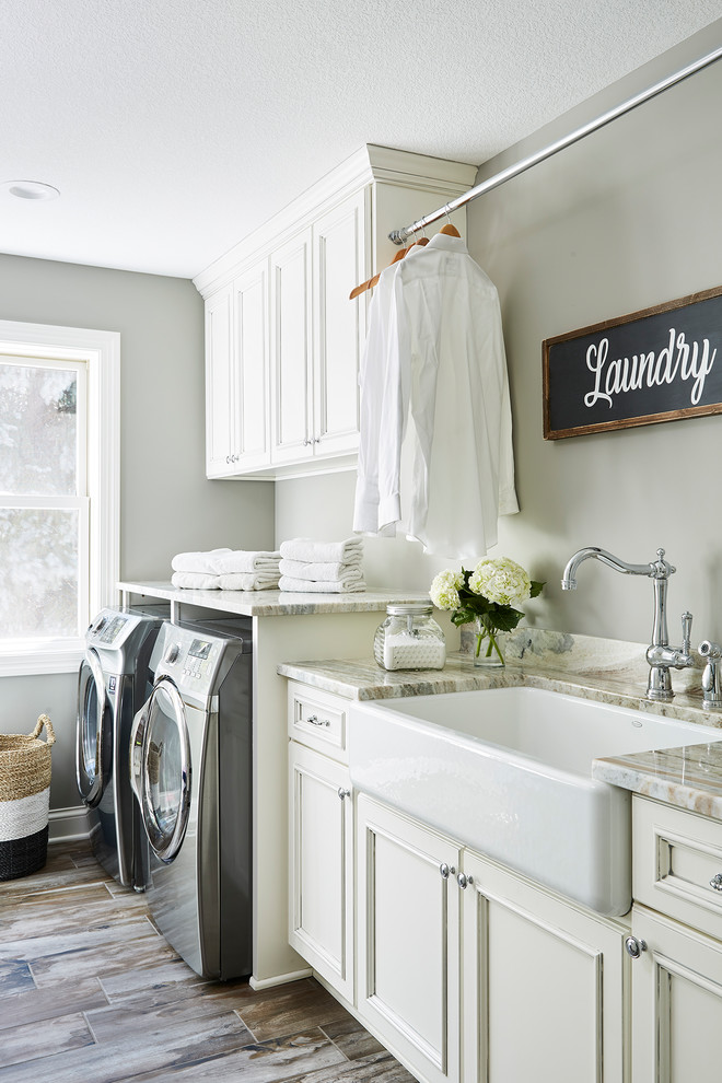 Large country galley dedicated laundry room in Minneapolis with a farmhouse sink, beaded inset cabinets, white cabinets, granite benchtops, grey walls, porcelain floors, a side-by-side washer and dryer, grey floor and multi-coloured benchtop.