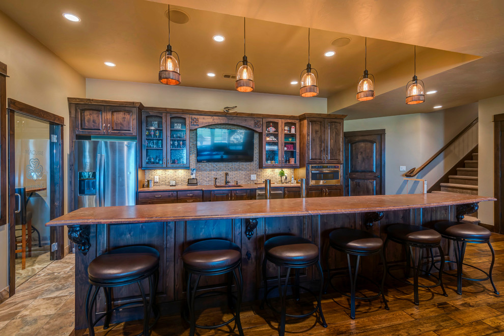 Inspiration for a large arts and crafts galley seated home bar in Denver with an undermount sink, raised-panel cabinets, dark wood cabinets, brown splashback, matchstick tile splashback, ceramic floors and brown floor.