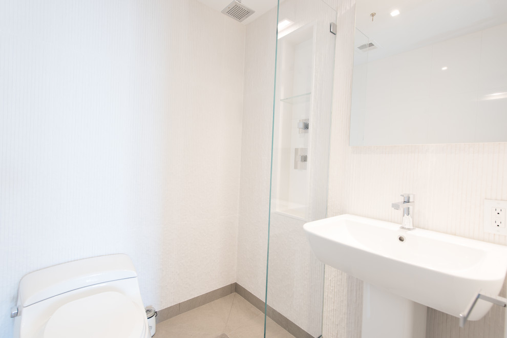 Photo of a large modern 3/4 bathroom in New York with a curbless shower, a wall-mount toilet, white tile, ceramic tile, white walls, ceramic floors, a pedestal sink, grey floor and an open shower.