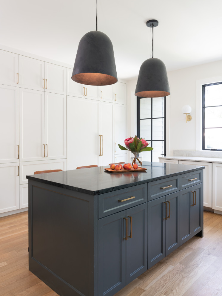 Mid-sized transitional u-shaped light wood floor and brown floor eat-in kitchen photo in Austin with flat-panel cabinets, blue cabinets, soapstone countertops, marble backsplash, paneled appliances, an island and black countertops