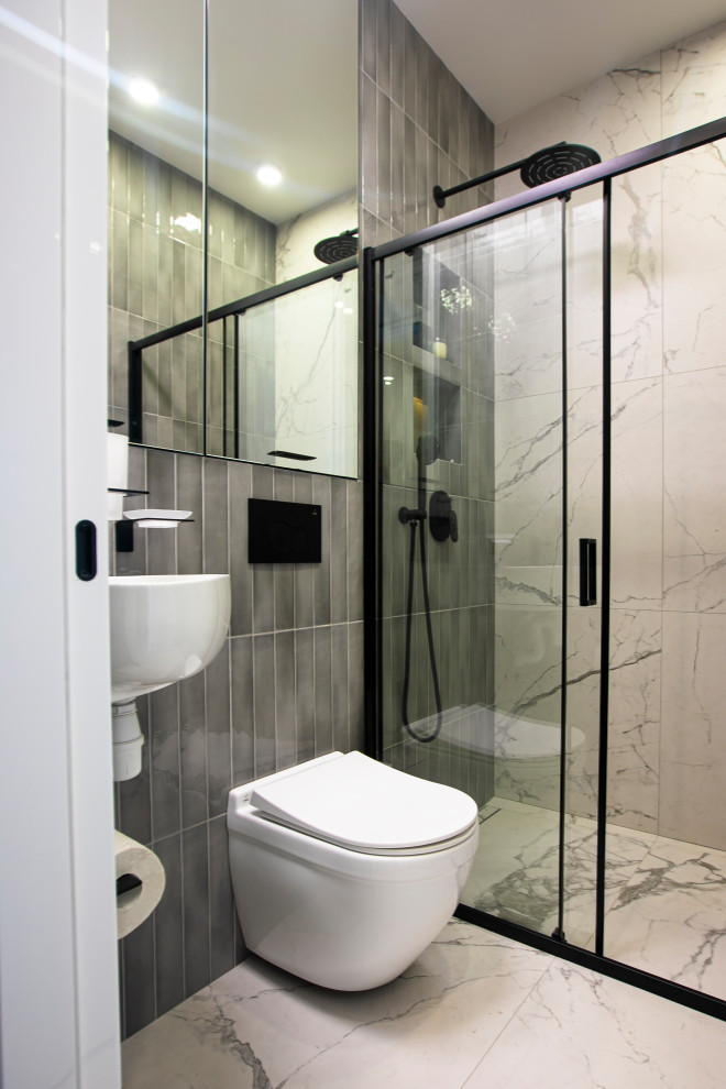 Exemple d'une salle d'eau grise et blanche tendance avec une douche à l'italienne, WC suspendus, un carrelage gris, des carreaux de céramique, un mur gris, un sol en carrelage de porcelaine, une cabine de douche à porte coulissante et meuble simple vasque.