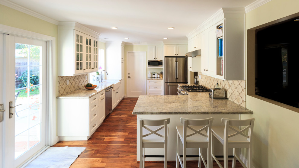Design ideas for a mid-sized traditional galley eat-in kitchen in San Francisco with a farmhouse sink, shaker cabinets, white cabinets, quartz benchtops, terra-cotta splashback, stainless steel appliances, medium hardwood floors, a peninsula and beige splashback.