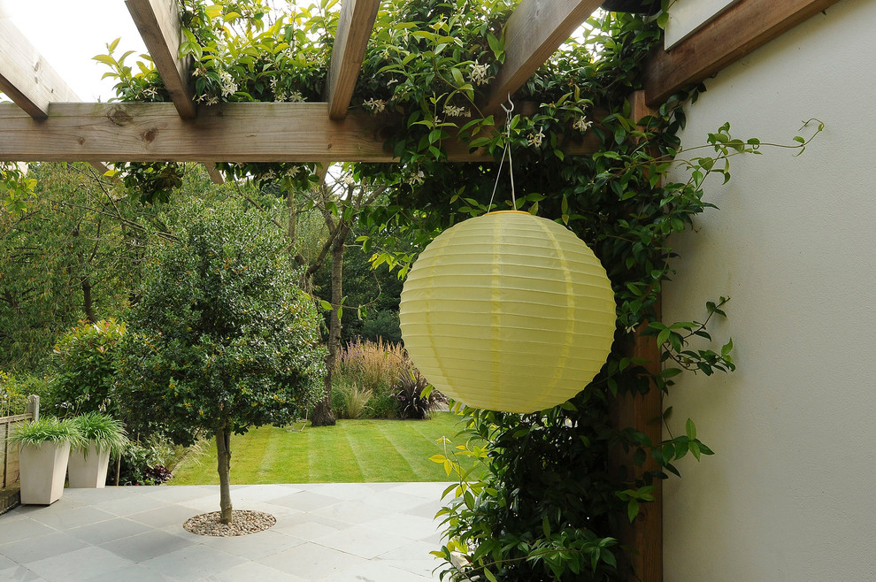 Inspiration for a contemporary backyard patio in London with natural stone pavers and a pergola.
