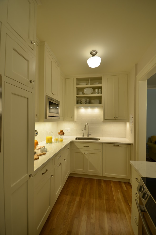 Inspiration for a small arts and crafts galley separate kitchen in Portland with an undermount sink, shaker cabinets, white cabinets, quartz benchtops, white splashback, subway tile splashback, stainless steel appliances and light hardwood floors.