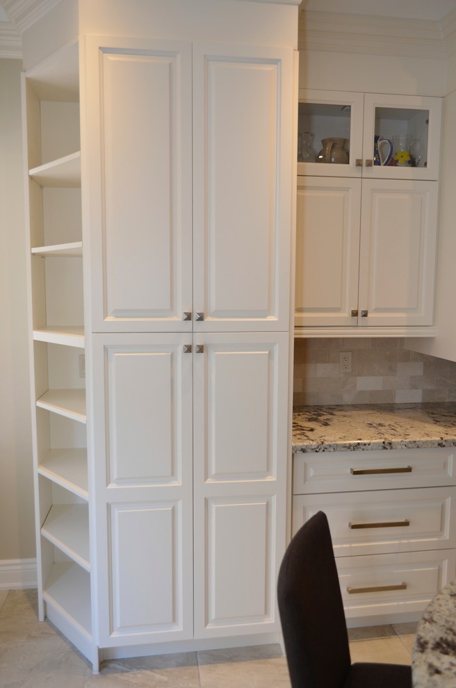 Inspiration for a mid-sized transitional l-shaped porcelain tile enclosed kitchen remodel in Toronto with an undermount sink, raised-panel cabinets, white cabinets, granite countertops, beige backsplash, stainless steel appliances and an island