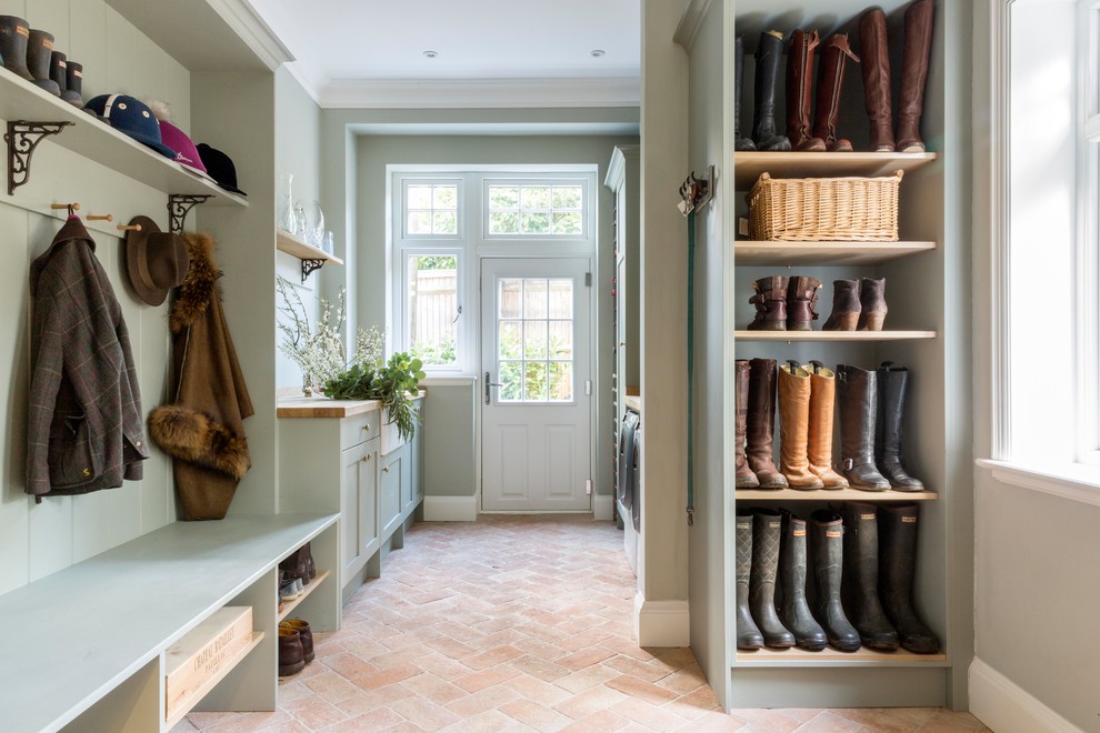Design ideas for a large traditional mudroom in Surrey with green walls, brick floors and orange floor.