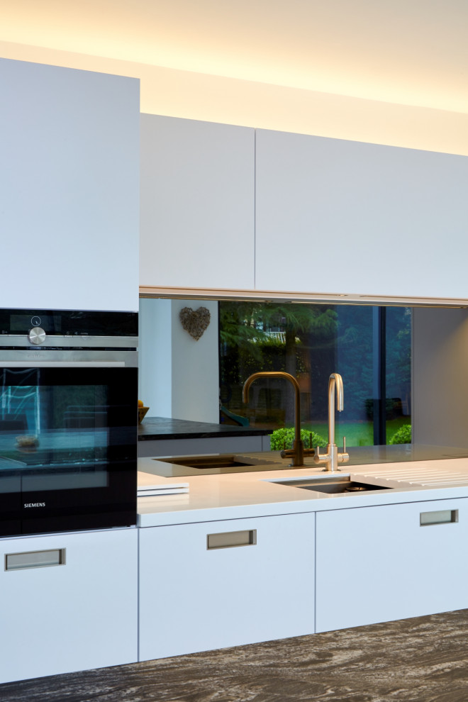 Idee per una cucina minimal di medie dimensioni con ante lisce, ante bianche, top in granito, paraspruzzi a effetto metallico, paraspruzzi a specchio, elettrodomestici da incasso e top blu