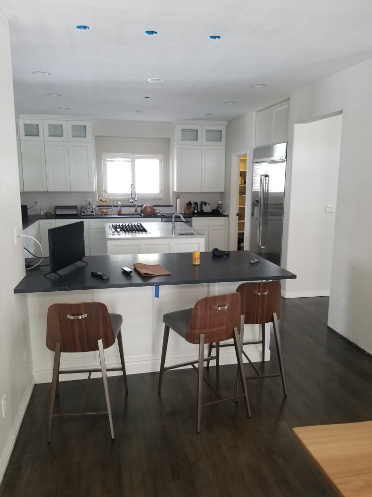 Inspiration for a large transitional u-shaped dark wood floor and brown floor eat-in kitchen remodel in Denver with an undermount sink, shaker cabinets, white cabinets, quartz countertops, stainless steel appliances, an island and black countertops