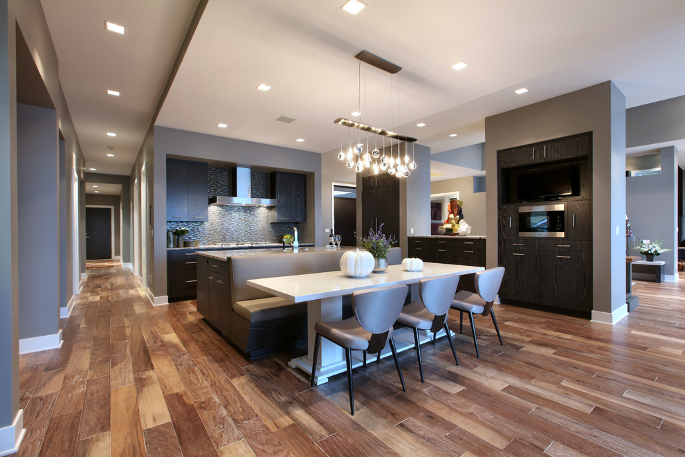 Inspiration for a large contemporary galley eat-in kitchen in Grand Rapids with flat-panel cabinets, grey cabinets, brown splashback, panelled appliances, medium hardwood floors and with island.