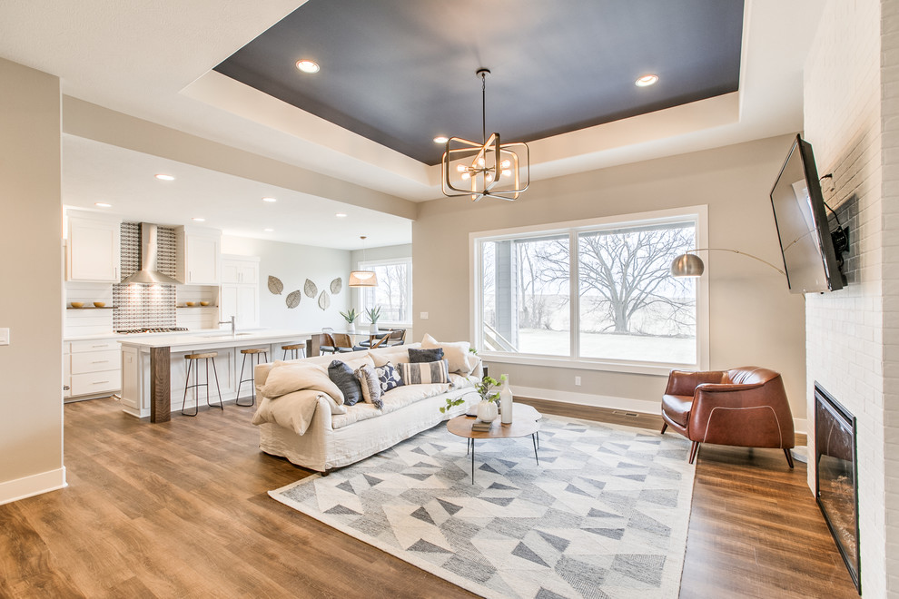 This is an example of a scandinavian open concept family room in Omaha with a standard fireplace, a brick fireplace surround and a wall-mounted tv.