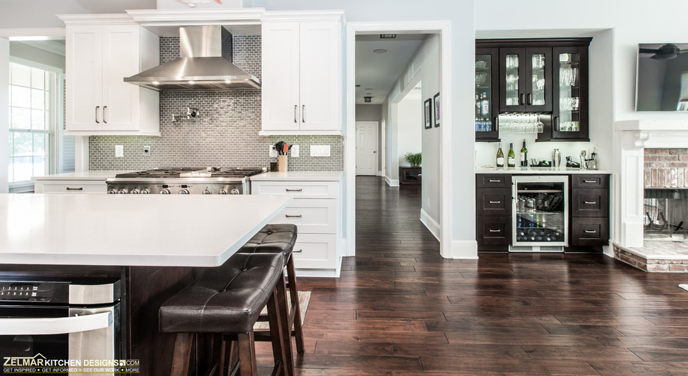This is an example of a large contemporary u-shaped eat-in kitchen in Orlando with shaker cabinets, white cabinets, with island, an undermount sink, quartz benchtops, green splashback, glass sheet splashback, stainless steel appliances and dark hardwood floors.