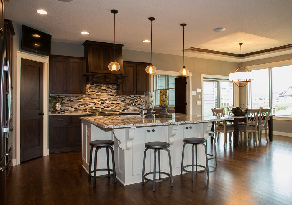 Example of a transitional l-shaped dark wood floor open concept kitchen design in Minneapolis with an undermount sink, flat-panel cabinets, granite countertops, multicolored backsplash, glass tile backsplash, stainless steel appliances and an island