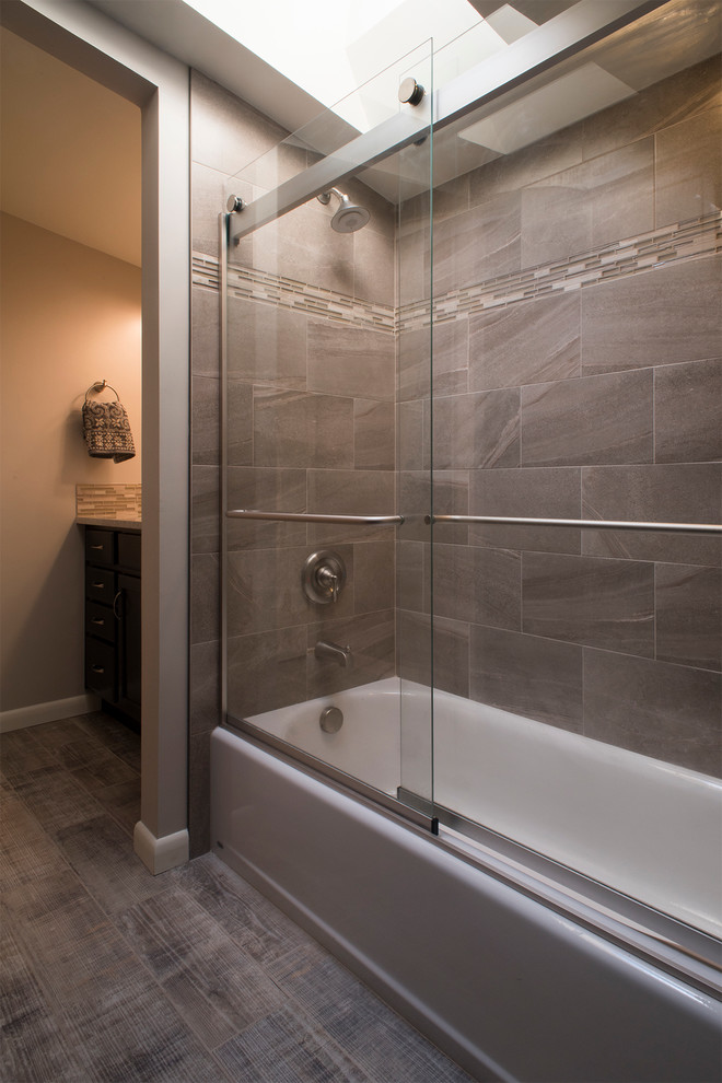 Design ideas for a mid-sized transitional kids bathroom in Denver with dark wood cabinets, an alcove tub, an alcove shower, a two-piece toilet, gray tile, ceramic tile, grey walls, ceramic floors, an undermount sink, granite benchtops and flat-panel cabinets.