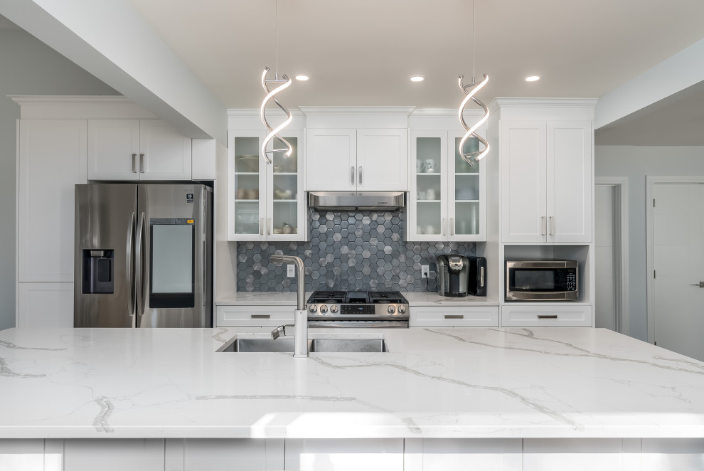 Example of a transitional kitchen design in Edmonton with shaker cabinets, white cabinets, quartzite countertops, gray backsplash, cement tile backsplash, stainless steel appliances, an island and white countertops